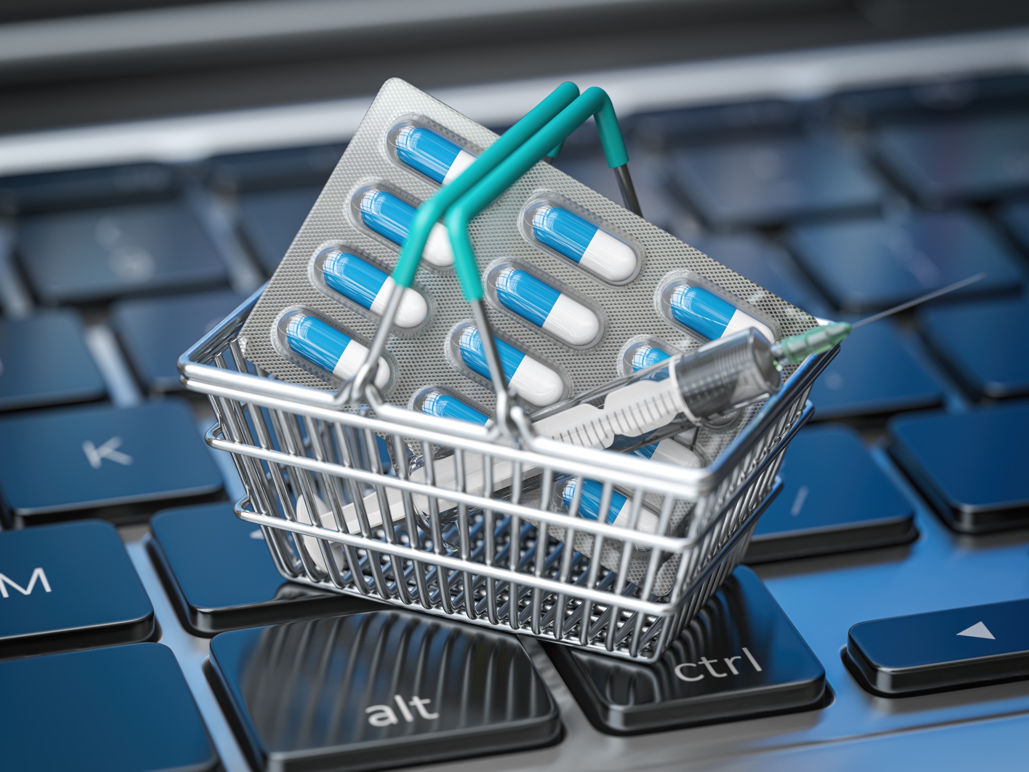 Shopping basket with pills and syrringe on laptop keyboard.. Buying pharma and medicines online.